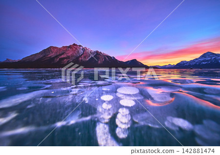Frozen Lake Methane Bubbles and Majestic Mountain at Vibrant Winter Sunset Frozen Lake Methane Bubbles and Majestic Mountain at Vibrant Winter Sunset 142881474