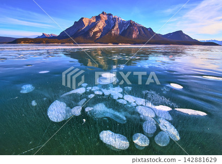Frozen Methane Bubbles in Clear Ice with Rugged Mountain and Winter Lake Scenery Frozen Methane Bubbles in Clear Ice with Rugged Mountain and Winter Lake Scenery 142881629