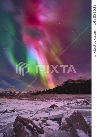 Northern Lights Over Frozen Lake with Winter Rocks and Snowy Landscape Northern Lights Over Frozen Lake with Winter Rocks and Snowy Landscape 142881632