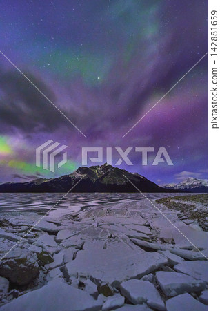 Frozen Lake Cracked Ice Snowcapped Mountain and Northern Lights in Winter Night Frozen Lake Cracked Ice Snowcapped Mountain and Northern Lights in Winter Night 142881659