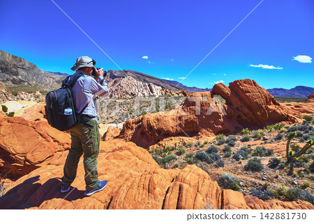 Photographer Exploring Red Sandstone Formations and Desert Landscape in Nevada Photographer Exploring Red Sandstone Formations and Desert Landscape in Nevada 142881730