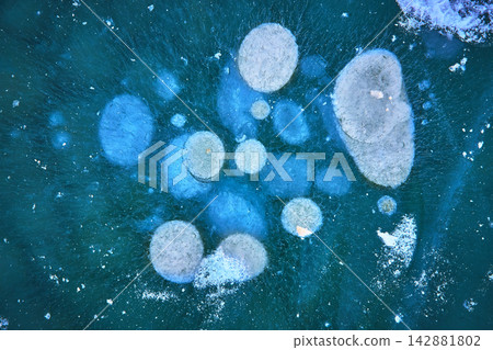 Aerial Frozen Lake Ice Patterns and Methane Bubbles in Vibrant Winter Blue 142881802
