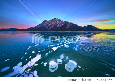 Frozen Lake Methane Bubbles and Mountain at Sunset in Winter Frozen Lake Methane Bubbles and Mountain at Sunset in Winter 142881866
