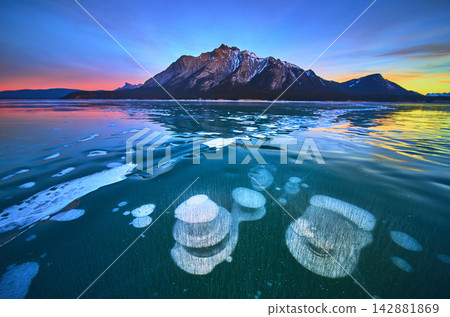 Frozen Methane Bubbles and Mountain Reflections on Winter Lake at Sunset Frozen Methane Bubbles and Mountain Reflections on Winter Lake at Sunset 142881869