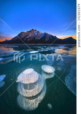 Frozen Methane Bubbles and Mountain Reflections on Winter Lake at Sunset Frozen Methane Bubbles and Mountain Reflections on Winter Lake at Sunset 142881874