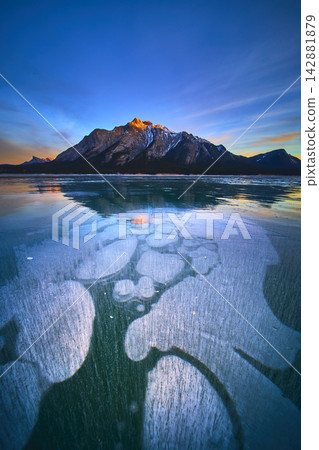 Frozen Lake Methane Bubbles Blue Ice and Snow Capped Mountain at Winter Sunset Frozen Lake Methane Bubbles Blue Ice and Snow Capped Mountain at Winter Sunset 142881879