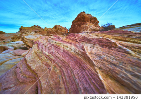 Colorful Sandstone Layers and Striations Under Blue Sky in Dramatic Desert Landscape Colorful Sandstone Layers and Striations Under Blue Sky in Dramatic Desert Landscape 142881950
