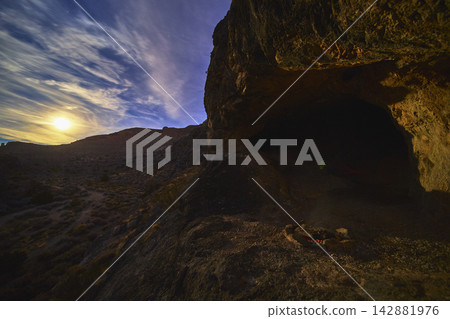 Cave Entrance and Moonlit Desert Landscape at Night with Campfire in Remote Nevada Cave Entrance and Moonlit Desert Landscape at Night with Campfire in Remote Nevada 142881976