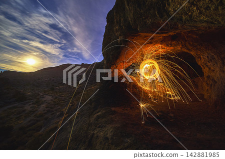 Peekaboo Canyon Cave with Steel Wool Sparks and Moonlit Desert Night Scene 142881985