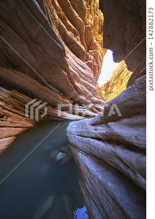 Slot Canyon with Water Pool and Sunlit Rock Walls in Remote Desert Landscape Slot Canyon with Water Pool and Sunlit Rock Walls in Remote Desert Landscape 142882173