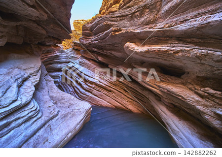 Layered Sandstone Walls and Water Pool in Dramatic Slot Canyon Formation Layered Sandstone Walls and Water Pool in Dramatic Slot Canyon Formation 142882262