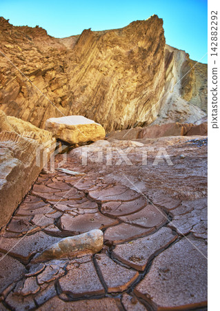 Cracked Desert Mud and Dramatic Rock Formations in Sunlit Southwest Landscape Cracked Desert Mud and Dramatic Rock Formations in Sunlit Southwest Landscape 142882292