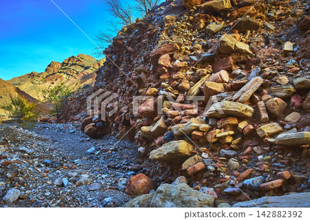 Rocky Canyon Wall and Desert Wash Under Blue Sky in Rugged Nevada Landscape 142882392