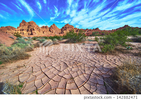 Cracked Desert Ground Red Rocks and Blue Sky in Valley of Fire Nevada Cracked Desert Ground Red Rocks and Blue Sky in Valley of Fire Nevada 142882471