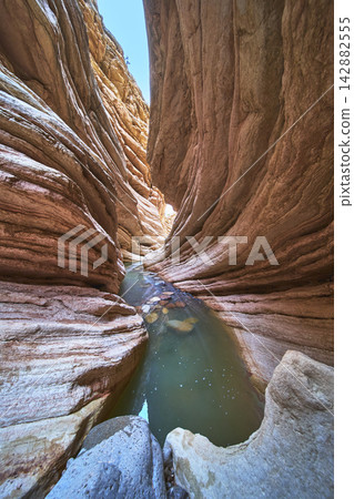 Slot Canyon Water Pool and Layered Sandstone Walls in Sunlit Desert Slot Canyon Water Pool and Layered Sandstone Walls in Sunlit Desert 142882555