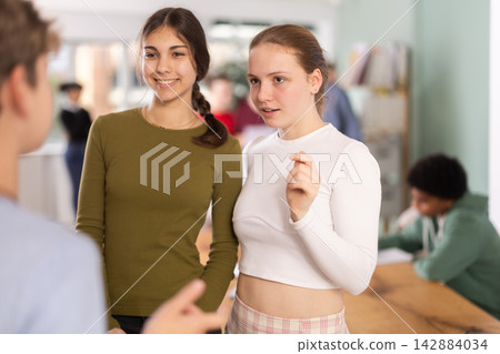 Two teenage girls communicate in a circle in a school Two teenage girls communicate in a circle in a school 142884034