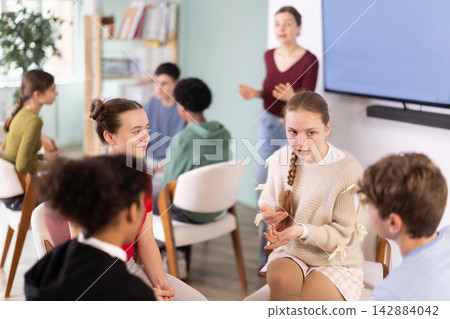 Two groups of students sit in a circle and discuss a topic 142884042