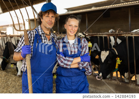 Two farmers standing in a cowshed Two farmers standing in a cowshed 142884193