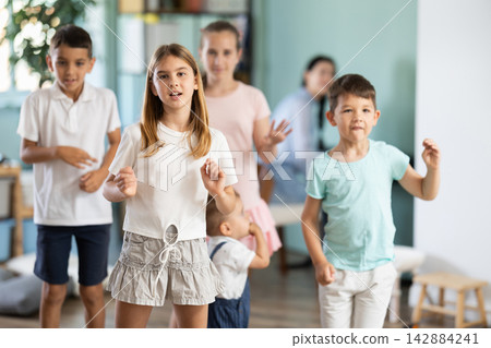 Group of children are dancing to live music, and babysitter is playing synthesizer. Group of children are dancing to live music, and babysitter is playing synthesizer. 142884241
