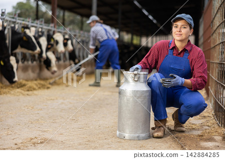 Young woman farmer with can works on dairy farm Young woman farmer with can works on dairy farm 142884285