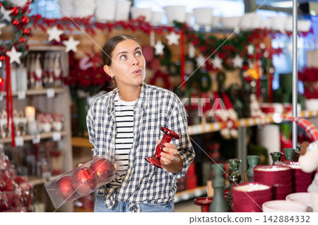 Young woman choosing christmas decorations in store Young woman choosing christmas decorations in store 142884332