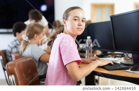 Portrait of female schoolgirl at computers in computer class Portrait of female schoolgirl at computers in computer class 142884410