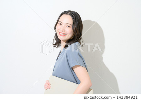 一位日本女性面帶微笑,手持筆記型電腦,背景為白色。 一位日本女性面帶微笑,手持筆記型電腦,背景為白色。 142884921