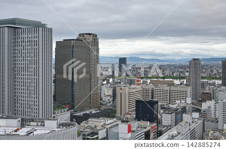A panoramic view of Osaka's Umeda district under a cloudy sky, overlooking the skyscrapers and cityscape. [Osaka Landscape Photo] 142885274