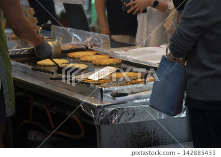 Cooking Korean mung bean pancakes bindaetteok on a griddle at street market 142885431