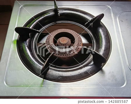 Close up top view of a single cast iron burner ring on a stainless steel gas stove top, kitchen appliance detail. Close up top view of a single cast iron burner ring on a stainless steel gas stove top, kitchen appliance detail. 142885587
