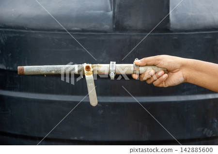 Person holding customized water pipe setup with rusted metal valve outdoors. Practical choice for DIY plumbing projects, pipeline fitting, and flow control. Person holding customized water pipe setup with rusted metal valve outdoors. Practical choice for DIY plumbing projects, pipeline fitting, and flow control. 142885600