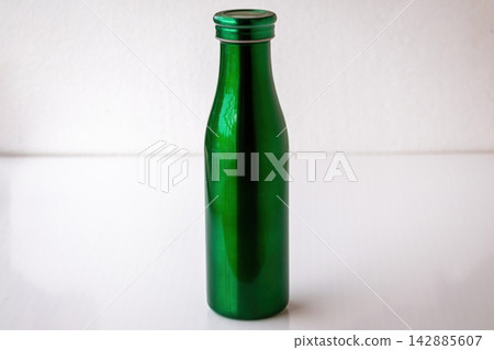 Reusable metallic green drink bottle isolated on white surface indoors. Durable metal thermos container for personal hydration, outdoor gym, and school use. Reusable metallic green drink bottle isolated on white surface indoors. Durable metal thermos container for personal hydration, outdoor gym, and school use. 142885607