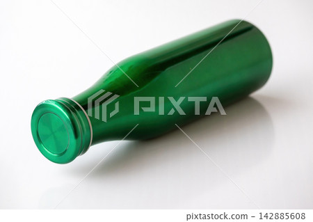 Metallic green water bottle lying down on clean white table surface. Reusable stainless steel container for daily personal hydration, travel, and fitness. Metallic green water bottle lying down on clean white table surface. Reusable stainless steel container for daily personal hydration, travel, and fitness. 142885608