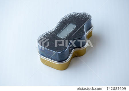 Instant shoe shine sponge in golden plastic case with transparent cover on white background. Essential accessory for leather footwear care, polish, and maintenance. Instant shoe shine sponge in golden plastic case with transparent cover on white background. Essential accessory for leather footwear care, polish, and maintenance. 142885609
