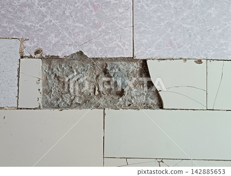 Damaged floor tiles with chipped off ceramic top layer revealing rough concrete underneath, macro shot of broken home surface requiring renovation. Damaged floor tiles with chipped off ceramic top layer revealing rough concrete underneath, macro shot of broken home surface requiring renovation. 142885653