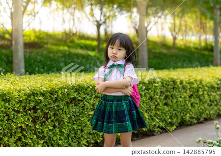 Upset Asian Little Schoolgirl Standing with Arms Crossed Outdoors Upset Asian Little Schoolgirl Standing with Arms Crossed Outdoors 142885795
