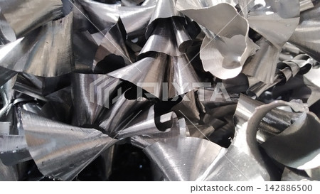 Steel scrap materials recycling. Aluminum chip waste after machining metal parts on a cnc lathe. Closeup twisted spiral steel shavings. Small roughness sharpness, Steel scrap materials recycling. Aluminum chip waste after machining metal parts on a cnc lathe. Closeup twisted spiral steel shavings. Small roughness sharpness, 142886500