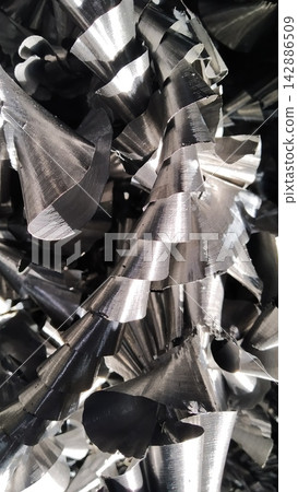 Steel scrap materials recycling. Aluminum chip waste after machining metal parts on a cnc lathe. Closeup twisted spiral steel shavings. Small roughness sharpness, Steel scrap materials recycling. Aluminum chip waste after machining metal parts on a cnc lathe. Closeup twisted spiral steel shavings. Small roughness sharpness, 142886509