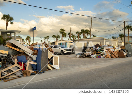 Rubbish and scrap disposed in heaps on street side after hurricane severely damaged houses in Florida home residential area. Consequences of natural disaster Rubbish and scrap disposed in heaps on street side after hurricane severely damaged houses in Florida home residential area. Consequences of natural disaster 142887395