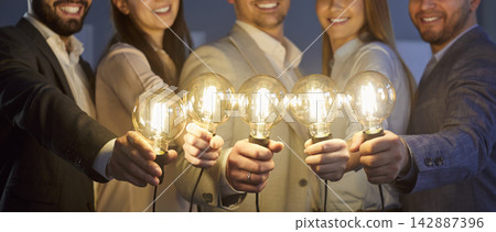 Creative idea and work of happy business team holding bright light bulbs and standing together 142887396