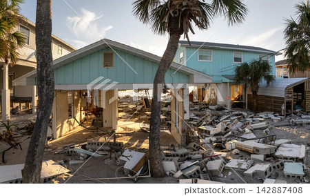 Storm surge caused by hurricane wind severe damaged residential houses on ocean shore. Natural disaster consequences in Florida Storm surge caused by hurricane wind severe damaged residential houses on ocean shore. Natural disaster consequences in Florida 142887408