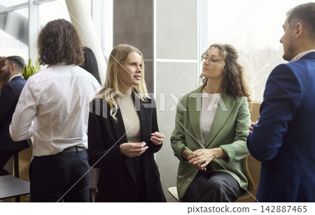 Diverse colleagues networking and discussing ideas at modern office lounge event 142887465