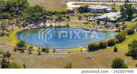 Scenic geothermal spring surrounded by nature, featuring saline water, swimmers floating peacefully, and a tranquil atmosphere connected to relaxation and healthy lifestyle. Scenic geothermal spring surrounded by nature, featuring saline water, swimmers floating peacefully, and a tranquil atmosphere connected to relaxation and healthy lifestyle. 142887466