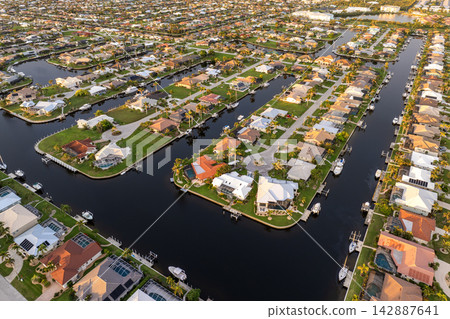 Sunset aerial view of Punta Gorda wealthy neighborhood. Expensive residential homes along canals reflect warm evening sky. Sunset aerial view of Punta Gorda wealthy neighborhood. Expensive residential homes along canals reflect warm evening sky. 142887641