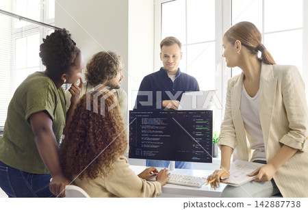 Programmers discuss code in team meeting at modern office with computer monitor Programmers discuss code in team meeting at modern office with computer monitor 142887738