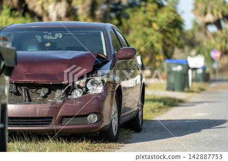 Vehicle damaged in traffic accident parked on street side in front of suburban houses. Insurance and transportation risk. Vehicle damaged in traffic accident parked on street side in front of suburban houses. Insurance and transportation risk. 142887753