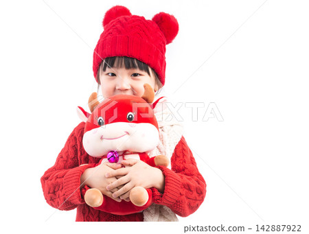 Smiling little girl hugging a red ox plush toy, celebrating the Year of the Ox, Chinese New Year theme. 142887922