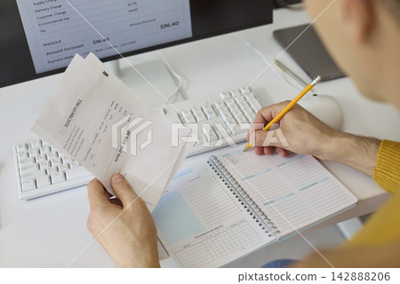 Man reviewing electricity bill and planning home budget with computer and notes Man reviewing electricity bill and planning home budget with computer and notes 142888206