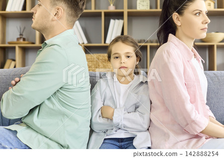 Upset child between parents after argument, family conflict and tension at home Upset child between parents after argument, family conflict and tension at home 142888254