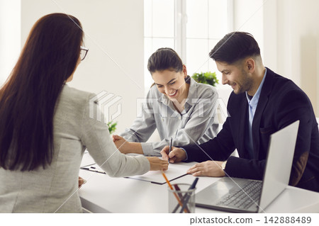 Happy young smiling family couple signing a contract agreement in the bank office 142888489